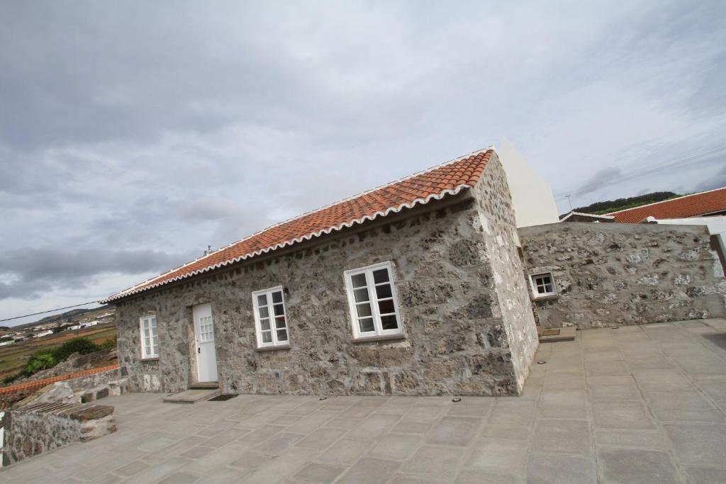 a stone building with white windows and a sky at Casa Branca da Chaminé in Cinco Ribeiras