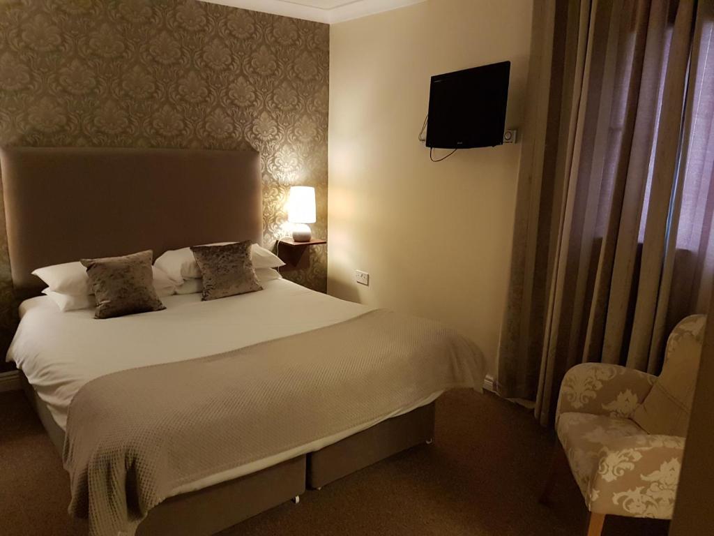 a bedroom with a bed and a chair and a television at Hatton's of Garadice in Garadice