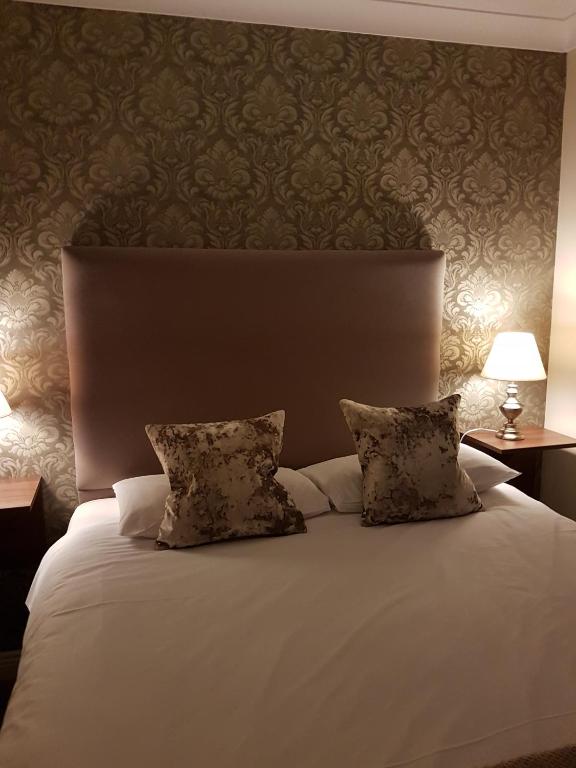 a bedroom with a white bed with two pillows at Hatton's of Garadice in Garadice