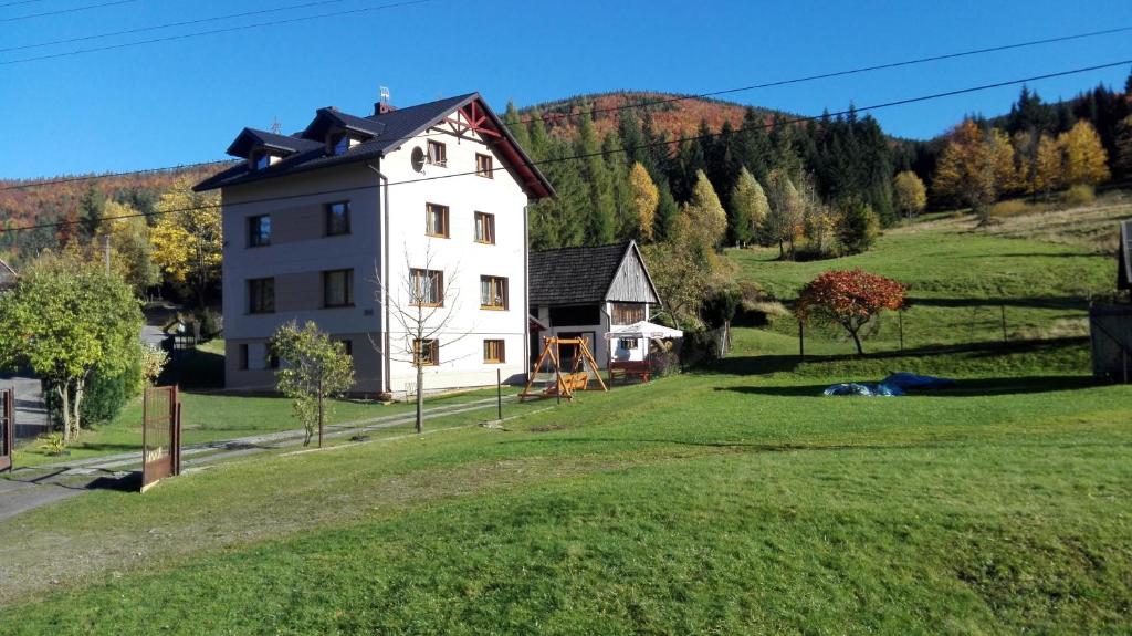 a white house on a hill with a green field at U Piotrka in Sopotnia Wielka