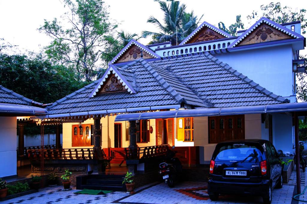 uma casa com um carro estacionado em frente em Mom&Pop Thyparambil Heritage em Alappuzha