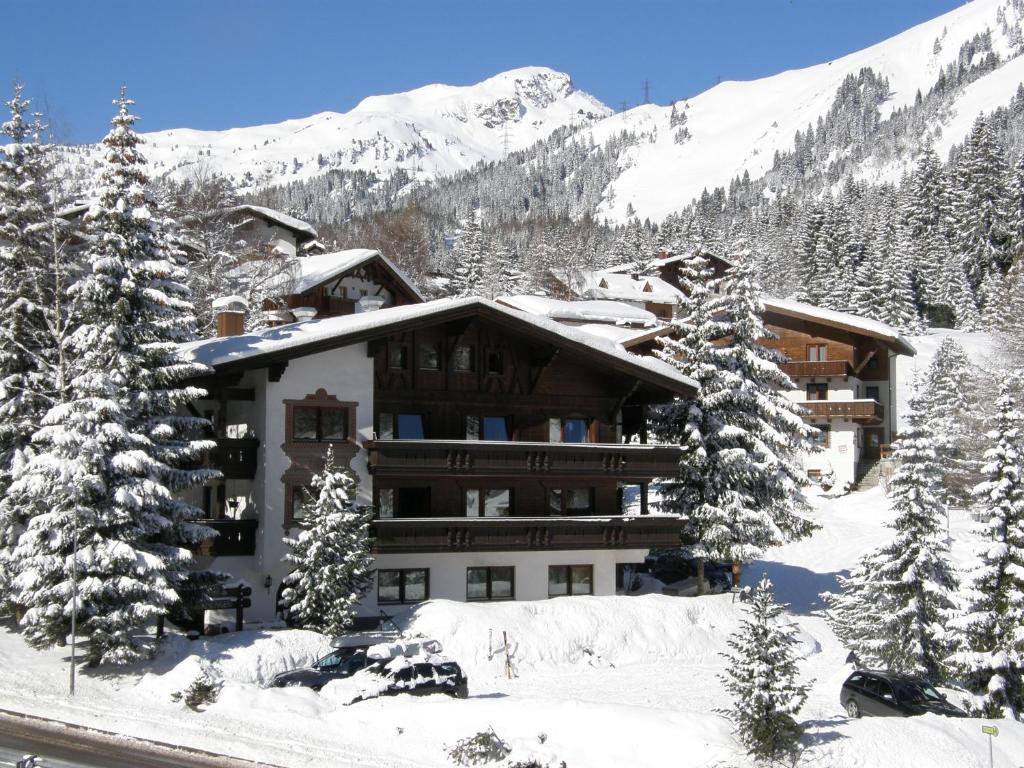 a building in the snow with trees and mountains at Appartements Kohlereck in Sankt Anton am Arlberg