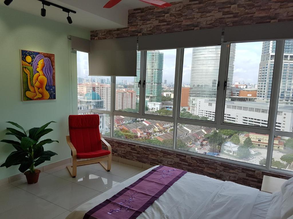 a bedroom with a red chair and large windows at Garden Apartment at Zenith in Petaling Jaya
