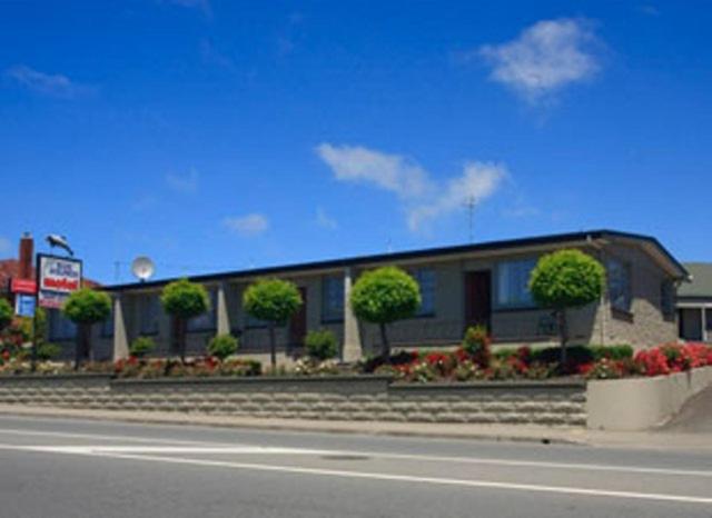 a building on the side of a road with flowers at Blue Dolphin Motel in Timaru