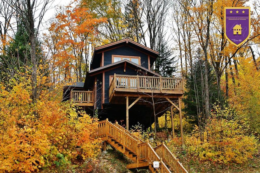 a large log cabin in the woods with a deck at Chalets Alpins - 17 Chemin Alpin in Stoneham