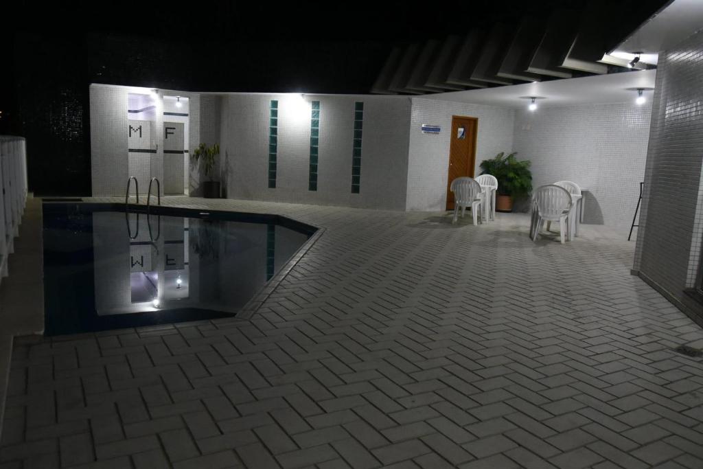 a pool in the middle of a building with chairs at Bevile Hotel in Cataguases