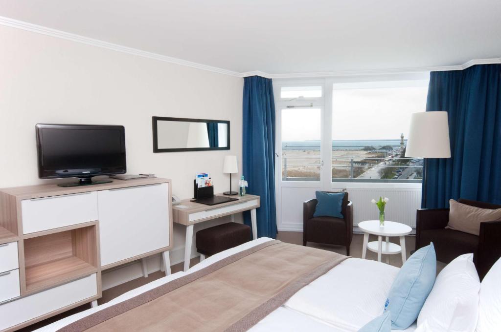 a hotel room with a bed and a television at Hotel Neptun in Warnemünde