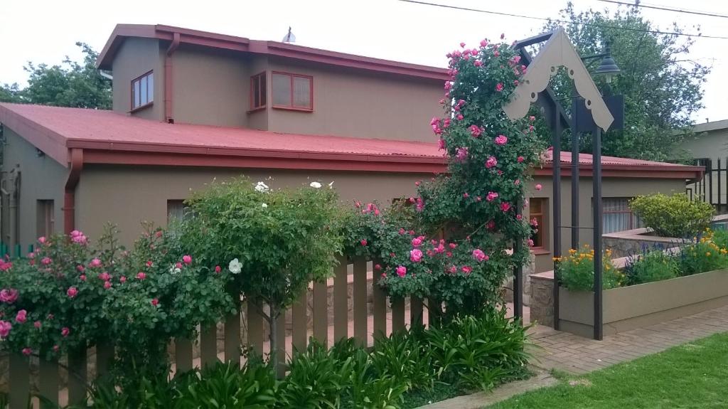 a fence in front of a house with flowers at Charilo in Dullstroom