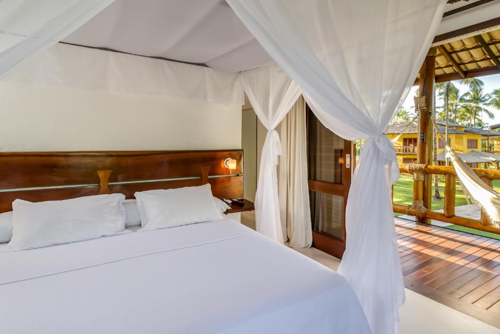 a bedroom with a white bed and a balcony at Villa dos Corais in Morro de São Paulo