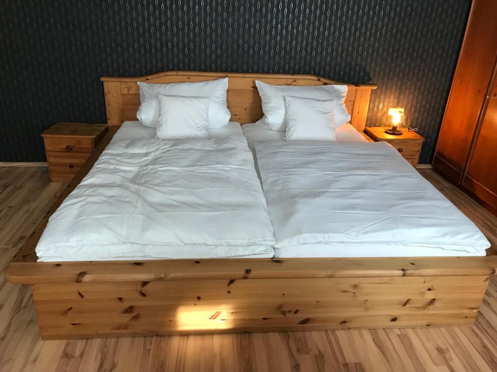 LindenfelsにあるFerienwohnung Giselaの大きな木製ベッド(白いシーツ、枕付)