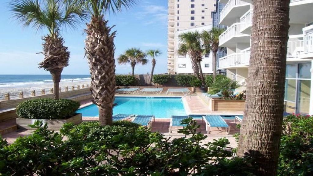 a swimming pool with palm trees and the beach at 405 Waters Edge in Myrtle Beach