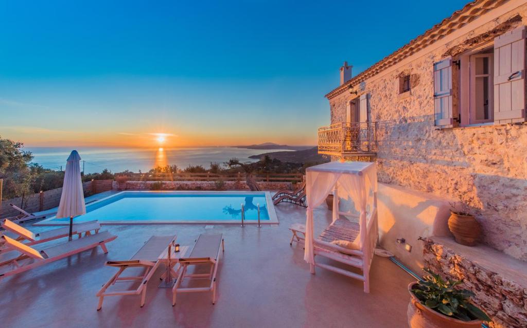 a villa with a swimming pool and a sunset at Villa Aria in Agios Nikolaos