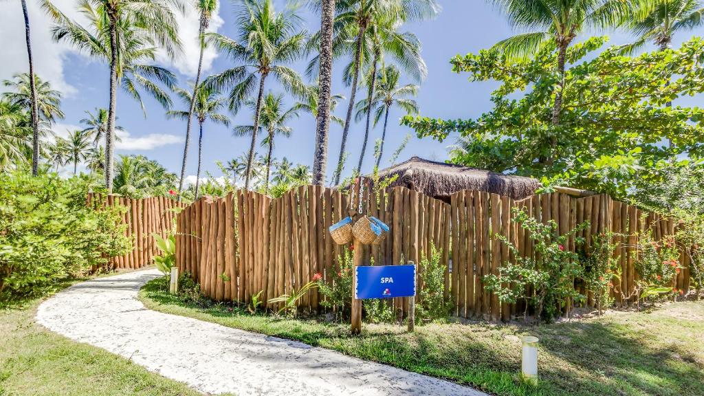 a wooden fence next to a path with palm trees at Villa dos Corais in Morro de São Paulo