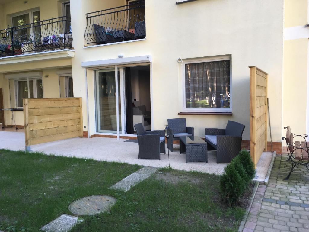 a patio with chairs and tables in front of a building at Pati Ferien Apartmens in Łukęcin