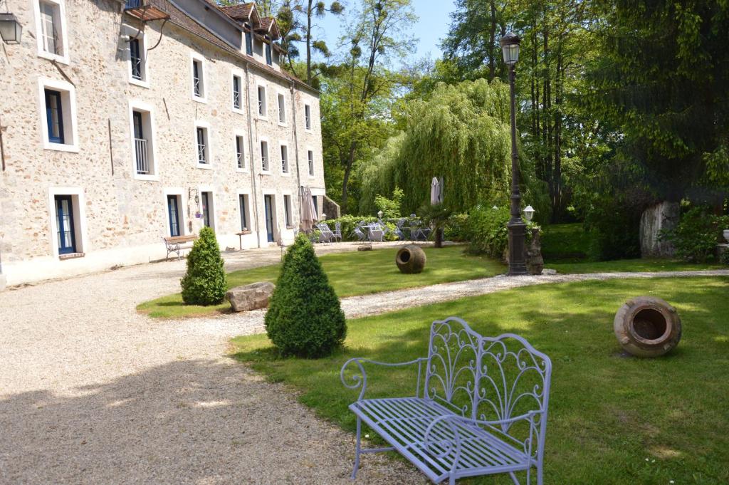 a blue bench sitting in the grass next to a building at Le Moulin de Pommeuse in Pommeuse