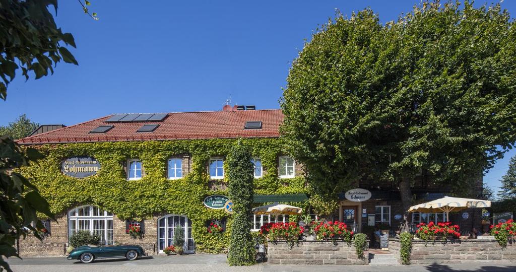 a building covered in ivy with a car parked in front at Land-gut-Hotel Lohmann in Drensteinfurt