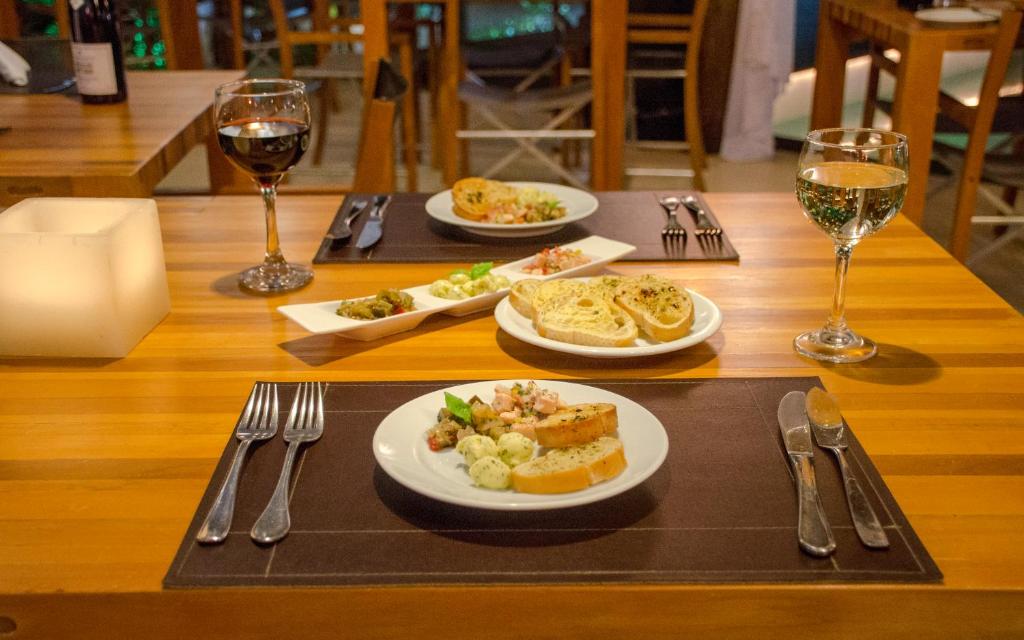 a table with plates of food and glasses of wine at Villa dos Corais in Morro de São Paulo
