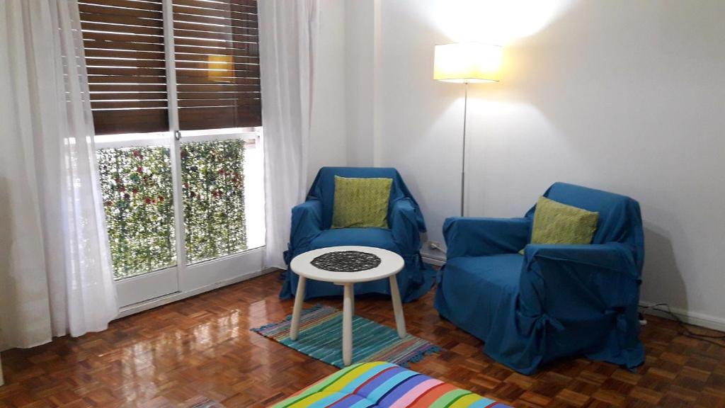 2 sillas azules y una mesa en una habitación con ventana en Distrito Palermo Apartment en Buenos Aires