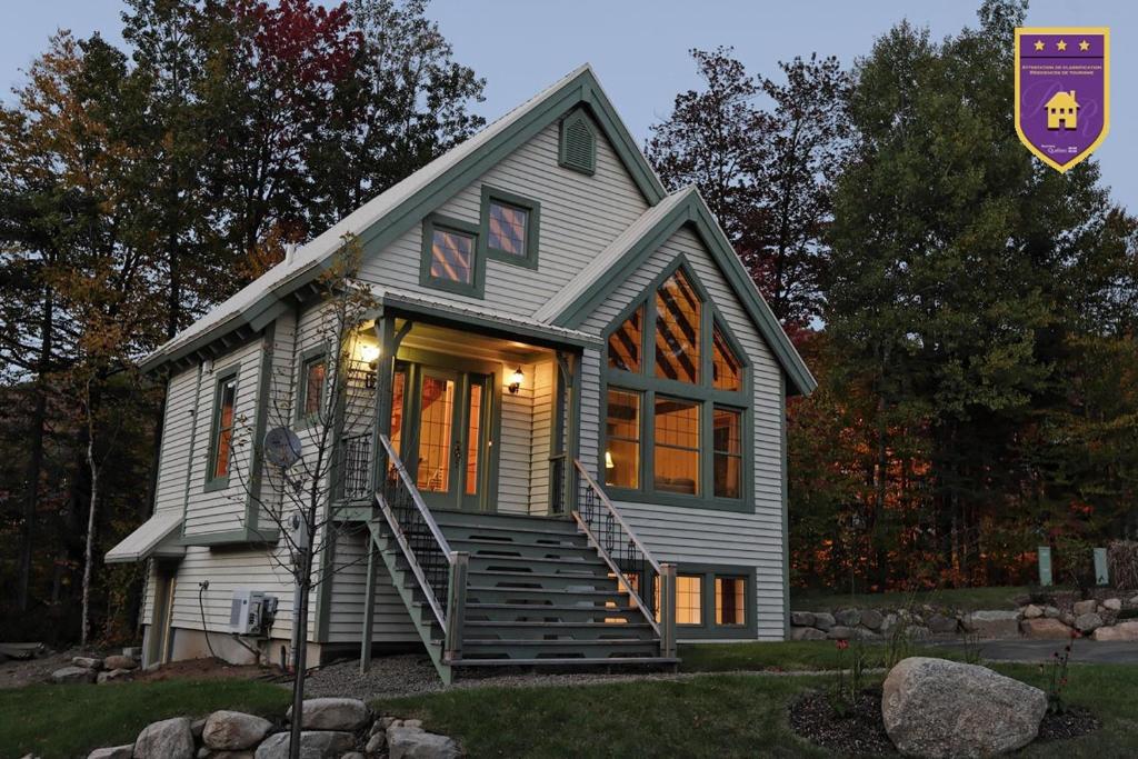 a small white house with stairs in front of it at Chalet 9017 Chemin des Alpages by Les Chalets Alpins in Stoneham