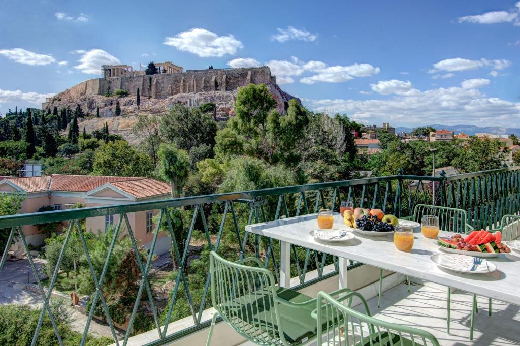 uma varanda com uma mesa com frutas e vista para a acrópole em Frixos Acropolis Luxury Apartment em Atenas