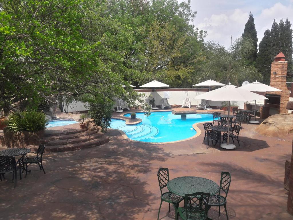 an outdoor pool with tables and chairs and umbrellas at Ecotel Midrand in Midrand