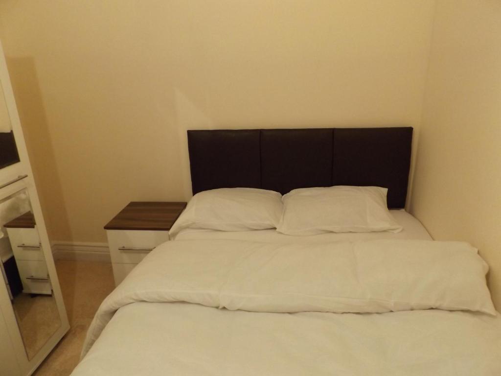 a bed with white sheets and a black headboard at Cotesheath house in Etruria