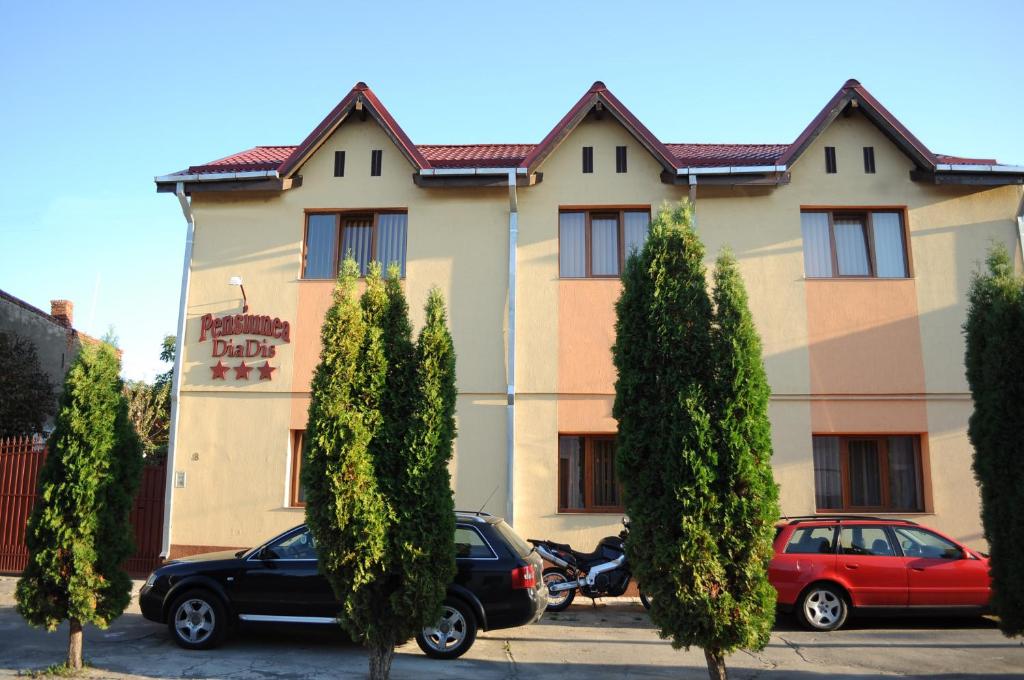 a building with two cars parked in front of it at Pensiunea Diadis in Cluj-Napoca
