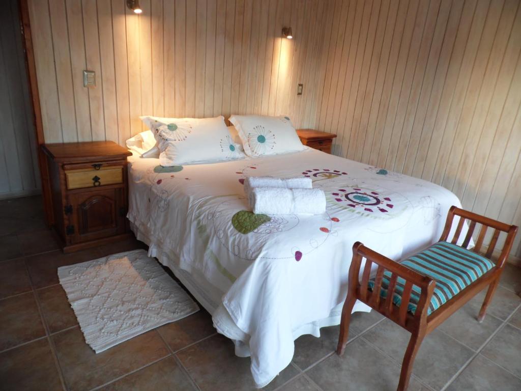 a bedroom with a large bed and a chair at Cabañas Urmeneta Sur in Tongoy