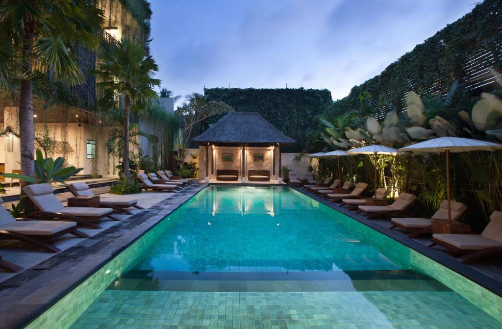 a pool at a hotel with chairs and umbrellas at Ubud Village Hotel in Ubud