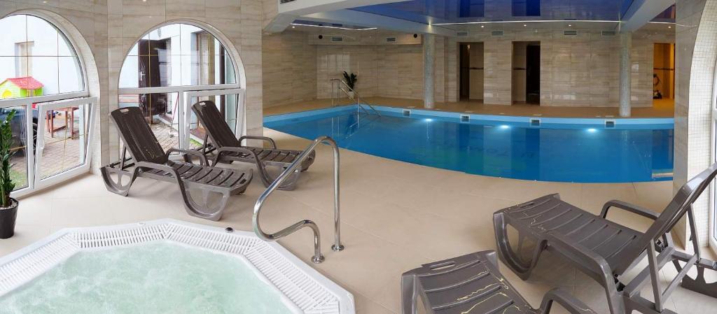uma piscina com cadeiras e uma banheira de hidromassagem em Pensjonat SPA u Tomasza em Niechorze