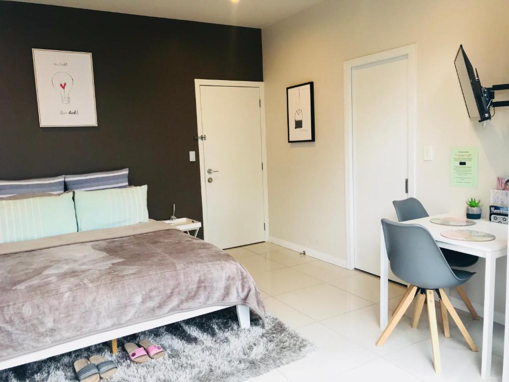 a bedroom with a bed and a desk and a table at New Market Cozy Room in Auckland