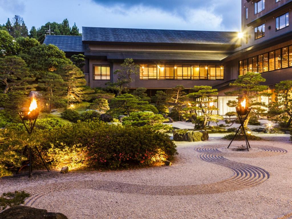 a building with lights in a garden at night at Hotel Gyokusen in Matsue