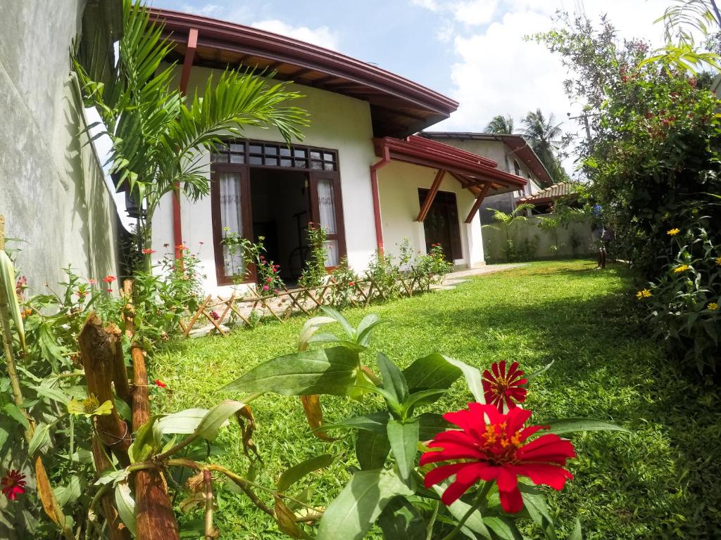 una casa con un patio verde con una flor roja en City Beach Apartment en Bentota