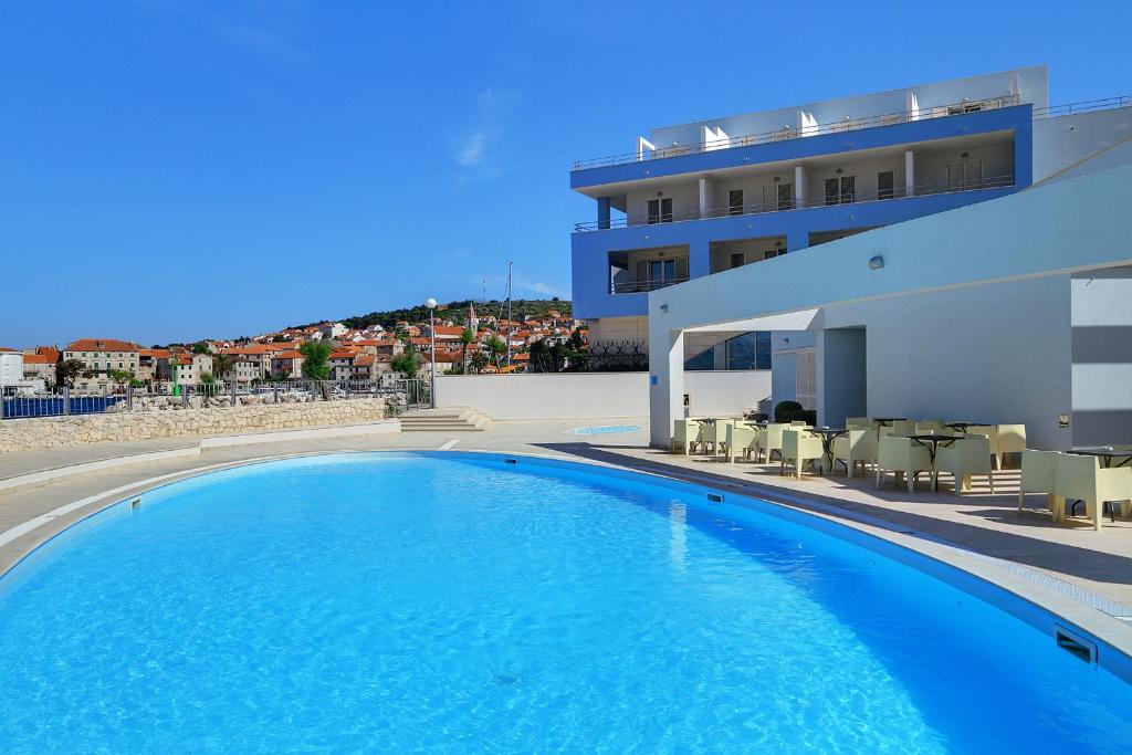 uma grande piscina azul ao lado de um edifício em Hotel Pastura em Postira