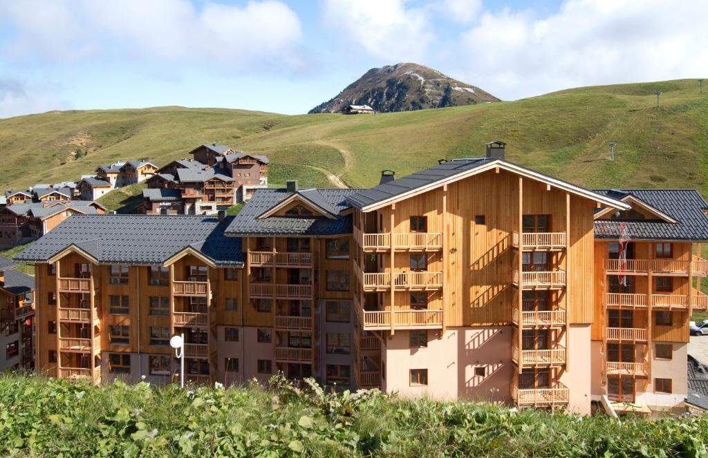 un groupe de bâtiments devant une montagne dans l'établissement Résidence Prestige Odalys Front de Neige, à Plagne Villages