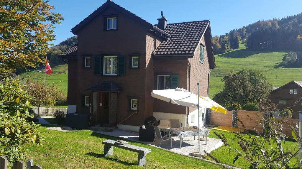 ein Haus mit einem Tisch und einem Sonnenschirm davor in der Unterkunft Ferienwohnung Eisenring in idyllischer Umgebung in Gähwil