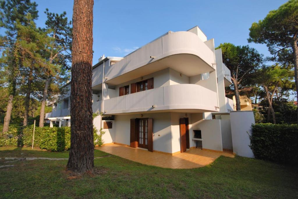 ein weißes Haus mit einem Baum davor in der Unterkunft Residence Verdecasa in Lignano Sabbiadoro