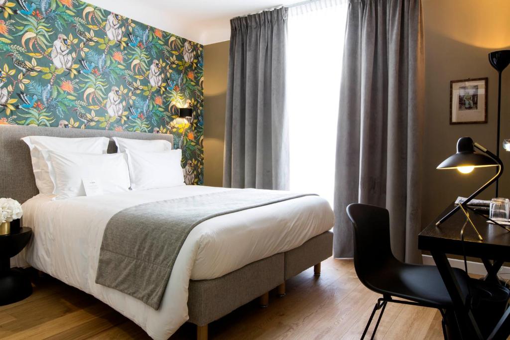 パリにあるオテル マティス エリゼのベッド、デスク、窓が備わるホテルルームです。