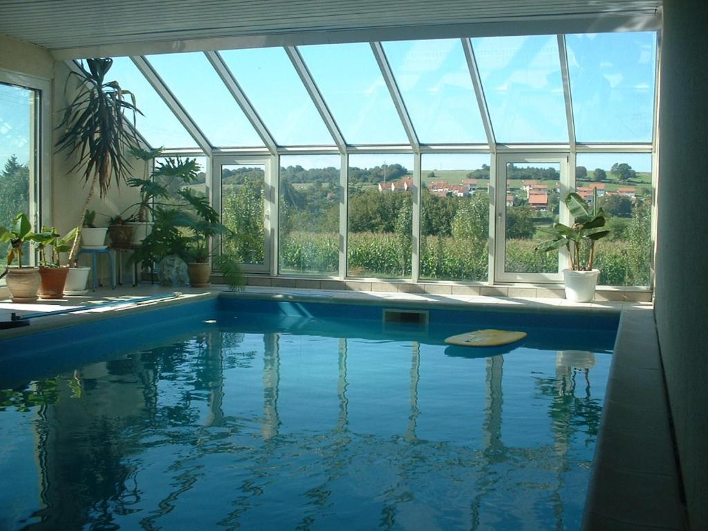 einen Pool in einem Haus mit einem großen Fenster in der Unterkunft Chambre d'hôtes LA COLOMBE in Xouaxange