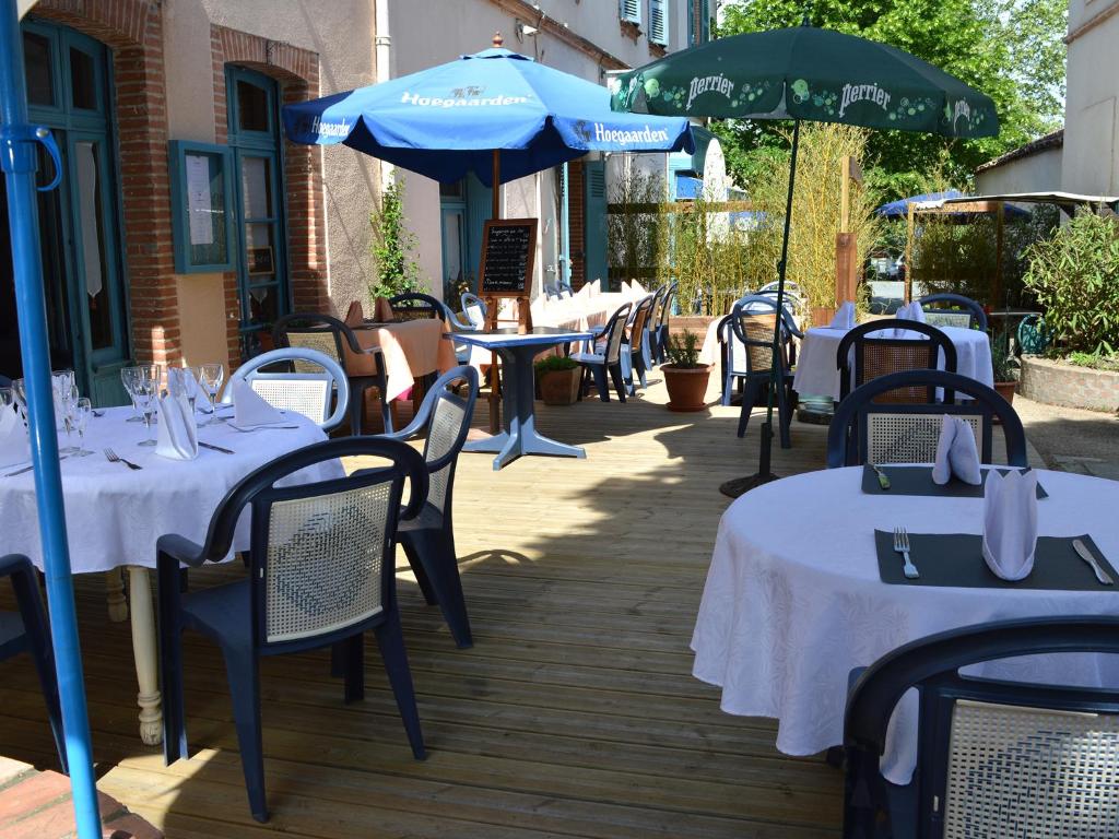 un grupo de mesas y sombrillas en un patio en Aux Lys d'Or, en Réalville