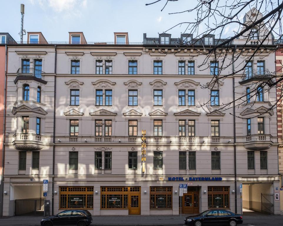 a large white building with cars parked in front of it at Hotel Bayernland in Munich