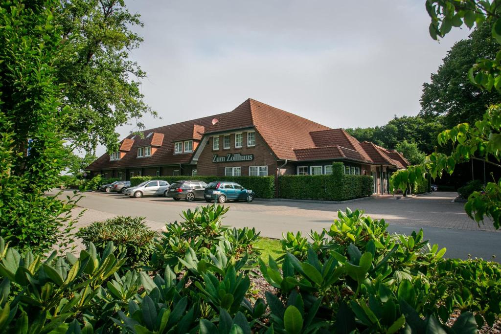 a building with cars parked in a parking lot at Residenz Hotel Zum Zollhaus in Rastede