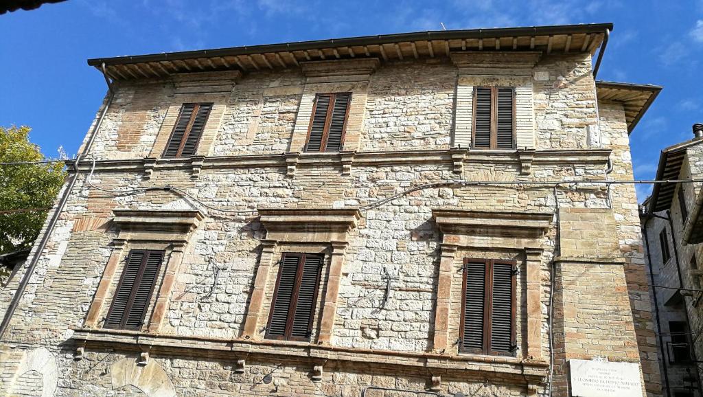 a tall stone building with windows and a blue sky at Palazzo Calocci appartamenti in Assisi in Assisi