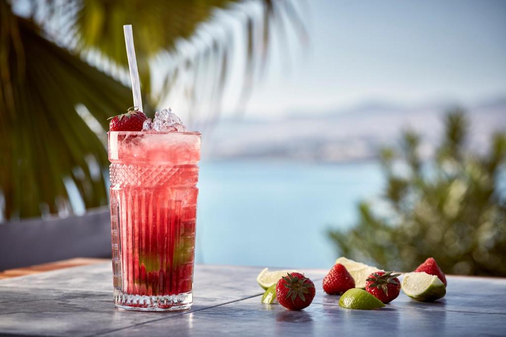 a drink sitting on a table with strawberries on it at Poseidon of Paros Hotel & Spa in Chrissi Akti