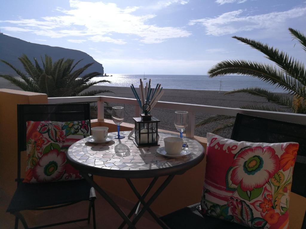 a table with wine glasses on a balcony with the ocean at Venturamar in Gran Tarajal