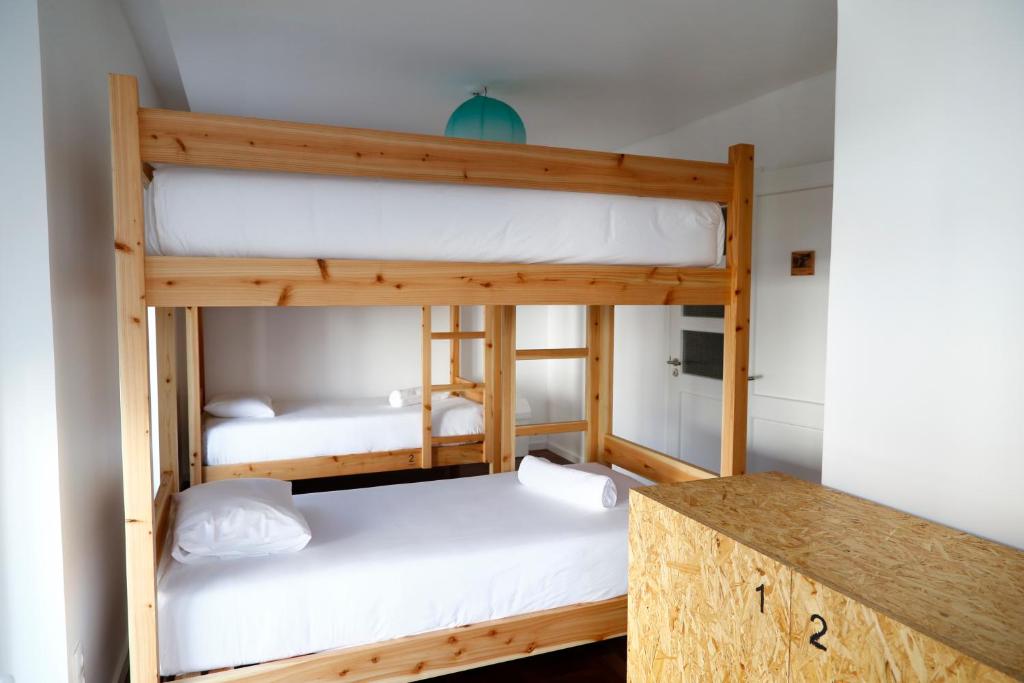 City's Hostel Ponta Delgada في بونتا ديلغادا: سريرين بطابقين في غرفة مع طاولة