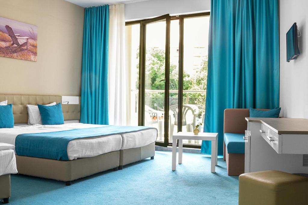 a bedroom with a bed and a window with blue curtains at Arena Mar Hotel and SPA in Golden Sands