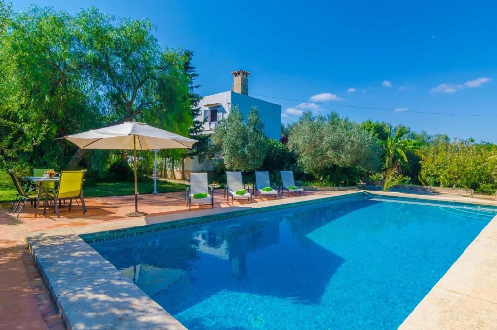 a swimming pool with chairs and an umbrella at Villa Garba in Felanitx