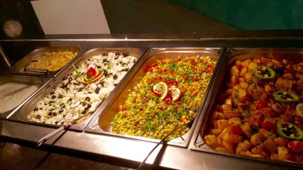 a buffet with four trays of different types of food at Arena Mar Hotel and SPA in Golden Sands