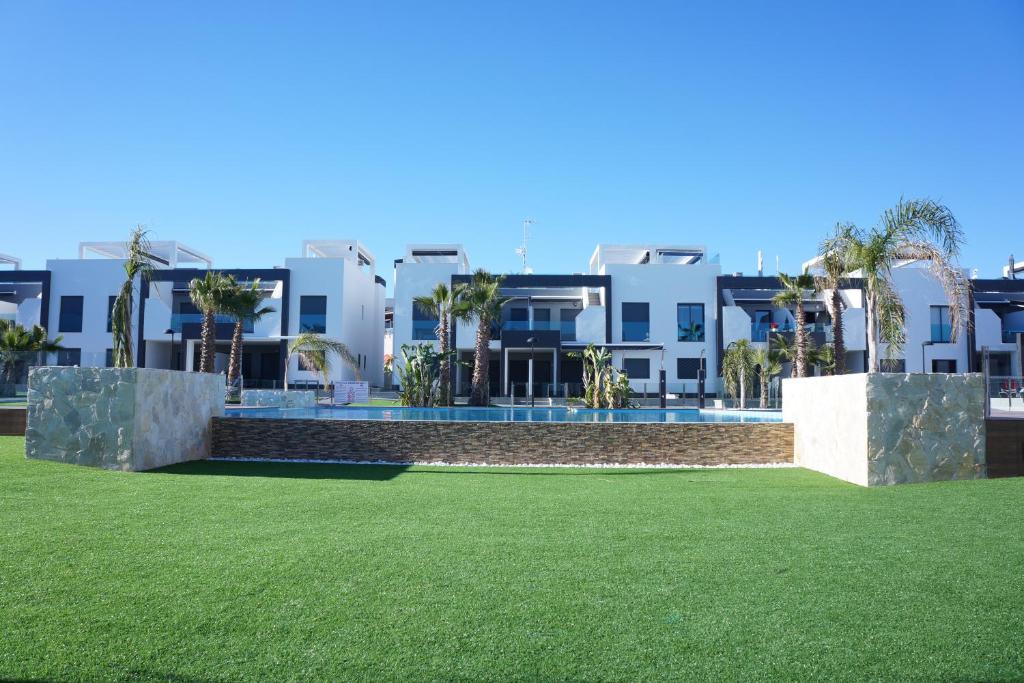 プレヤス・デ・オリフエラにあるApartment Oasis Beach La Zeniaの白い建物の前の芝生